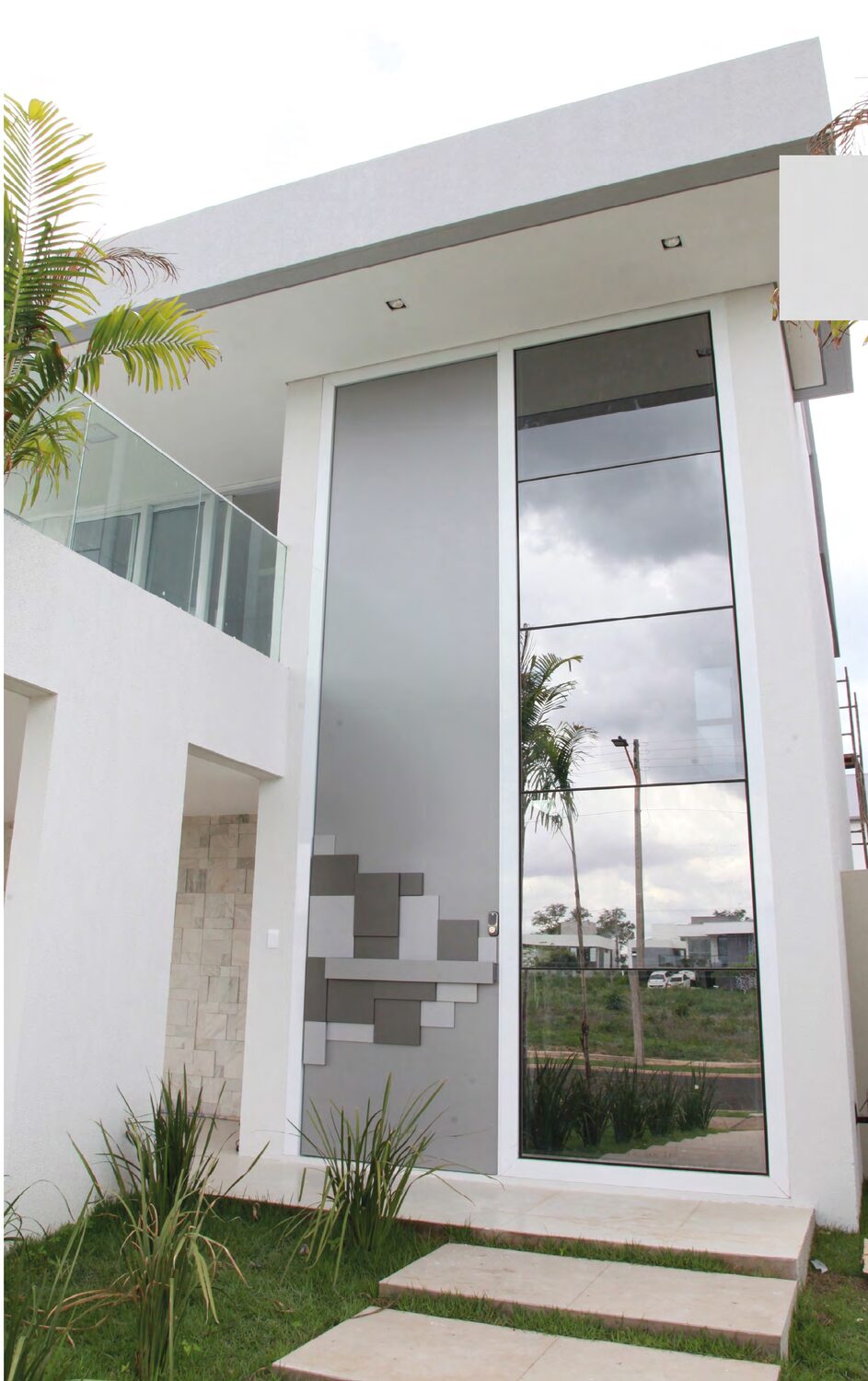 Fachada residencial moderna con ventanal alto y detalles en ACM gris