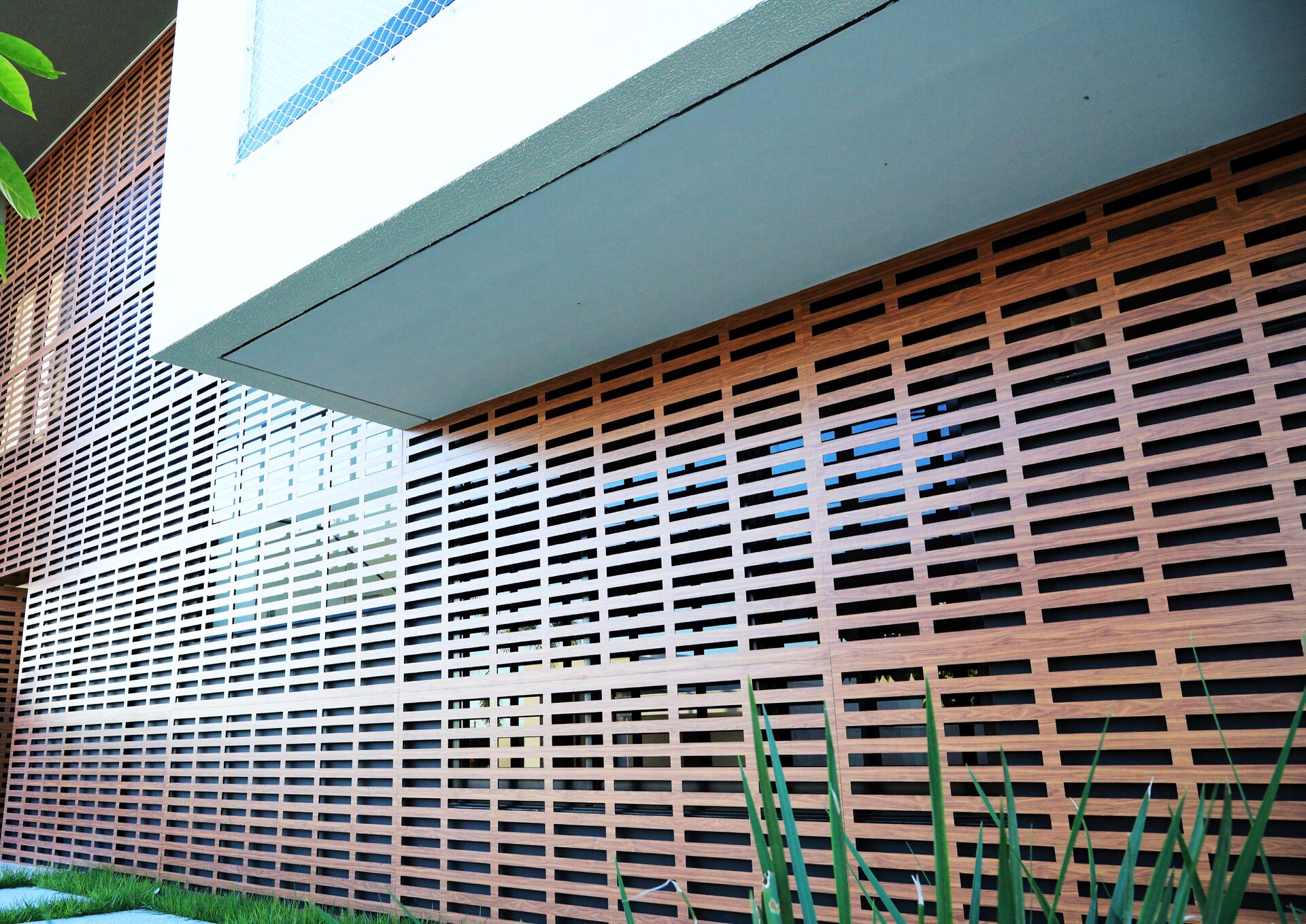 Fachada residencial revestida con panel calado símil madera en ACM