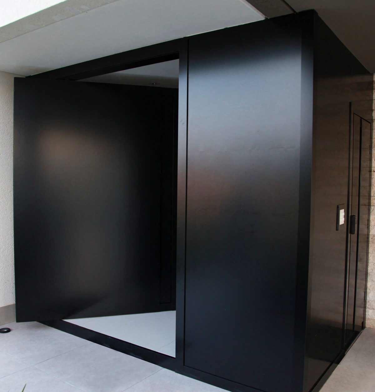 Puerta pivotante en ACM negro mate en el ingreso de una vivienda